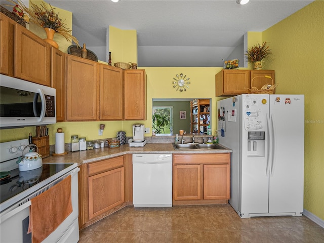 kitchen featuring a textured ceiling, white appliances, and sink