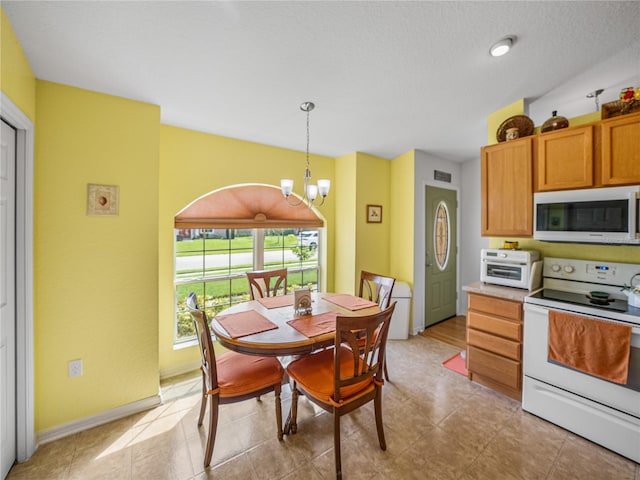 kitchen with a textured ceiling, white appliances, a chandelier, and decorative light fixtures