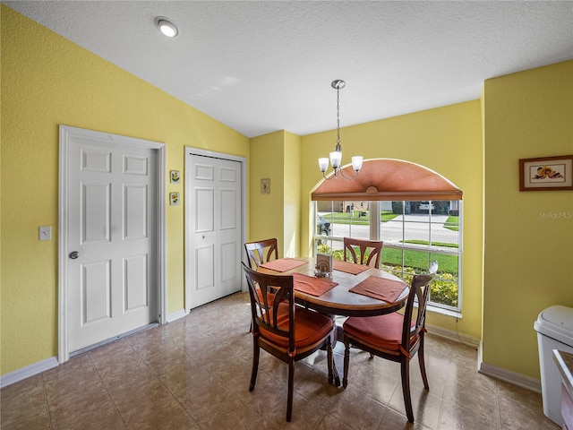 dining area with a notable chandelier, vaulted ceiling, and a textured ceiling