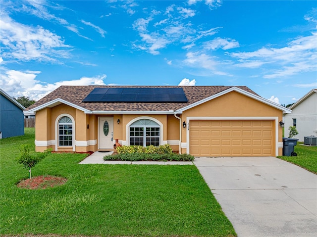 single story home featuring cooling unit, a front yard, solar panels, and a garage