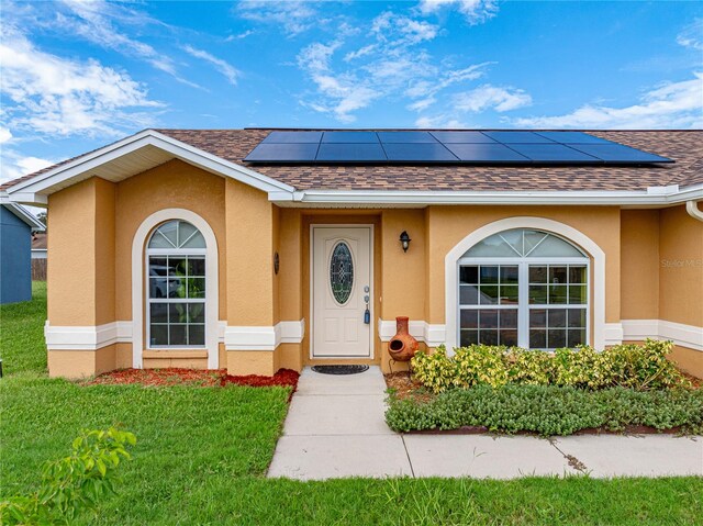 view of exterior entry with solar panels and a lawn