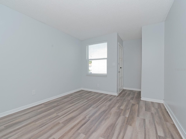 spare room featuring light hardwood / wood-style floors and a textured ceiling