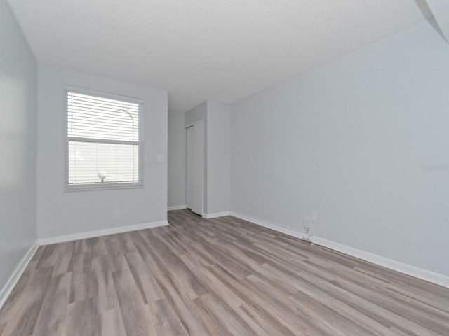 spare room with light hardwood / wood-style floors and a textured ceiling