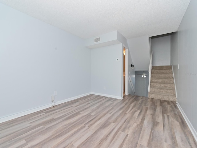 unfurnished living room featuring a textured ceiling and light hardwood / wood-style floors