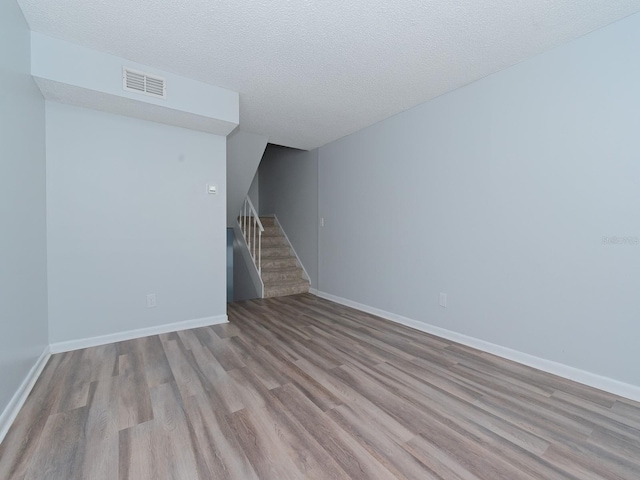 unfurnished living room with a textured ceiling and light hardwood / wood-style flooring