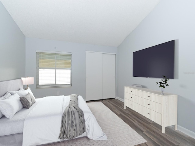 bedroom with vaulted ceiling, a closet, and dark wood-type flooring