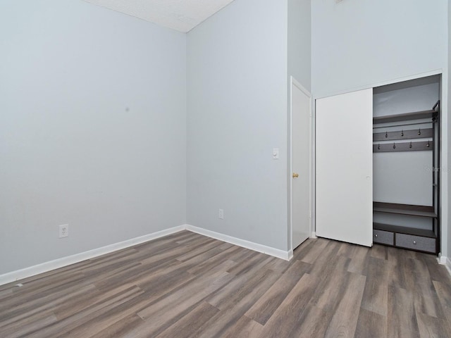 unfurnished bedroom with a textured ceiling, dark hardwood / wood-style floors, and a closet