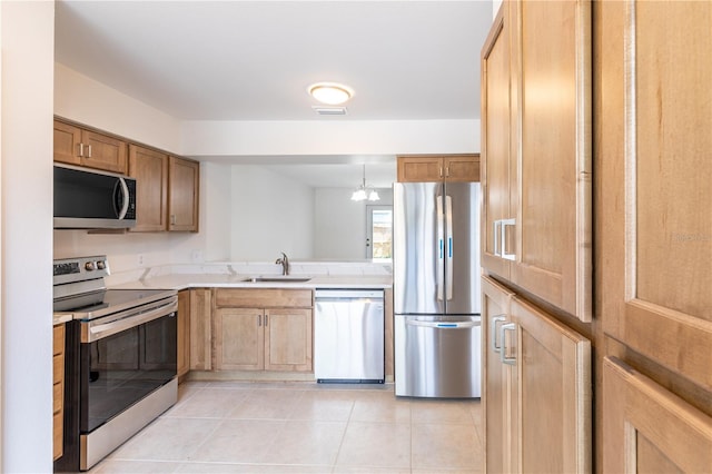 kitchen featuring pendant lighting, light tile patterned flooring, appliances with stainless steel finishes, and sink