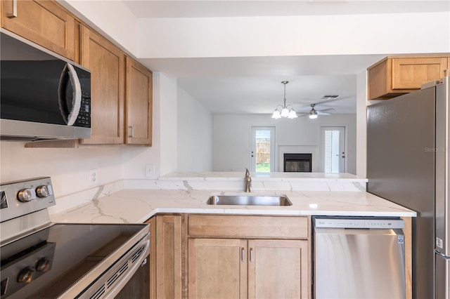 kitchen featuring ceiling fan, appliances with stainless steel finishes, hanging light fixtures, and sink