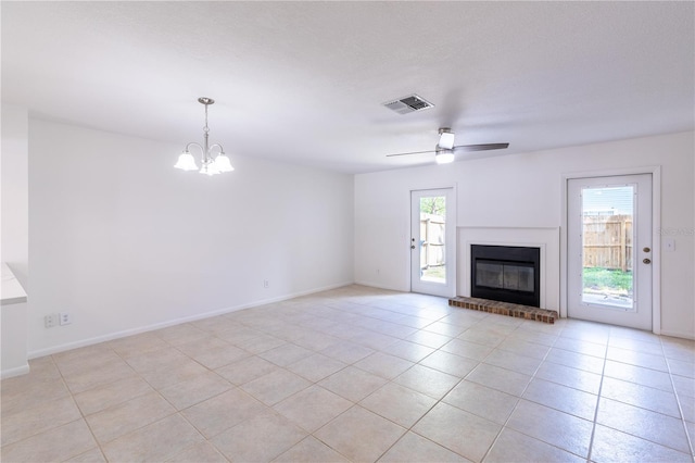 unfurnished living room featuring ceiling fan with notable chandelier, light tile patterned floors, and a brick fireplace