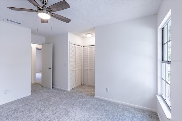 unfurnished bedroom with ceiling fan, a closet, light carpet, and multiple windows