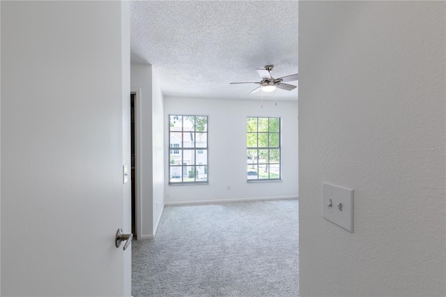 spare room featuring a textured ceiling, ceiling fan, and light colored carpet