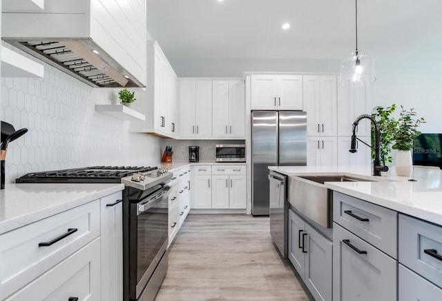 kitchen with white cabinets, backsplash, stainless steel appliances, decorative light fixtures, and premium range hood