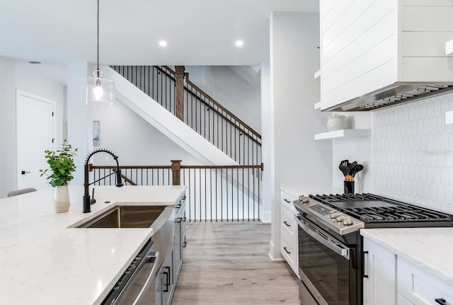 kitchen with pendant lighting, light wood-type flooring, white cabinetry, decorative backsplash, and stainless steel appliances