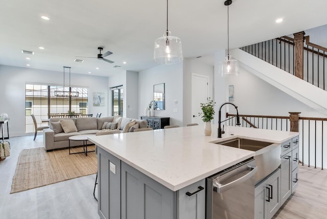 kitchen featuring an island with sink, light hardwood / wood-style flooring, decorative light fixtures, ceiling fan, and stainless steel dishwasher