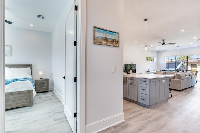 interior space with gray cabinetry, light hardwood / wood-style floors, ceiling fan, and decorative light fixtures