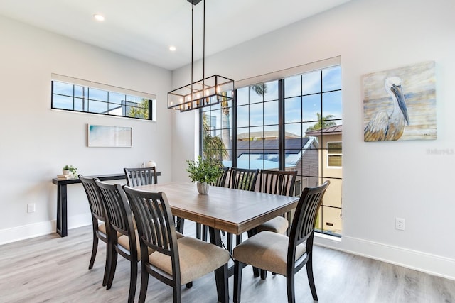 dining space with light hardwood / wood-style flooring and a notable chandelier