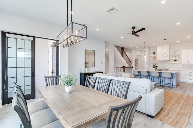 dining area featuring ceiling fan with notable chandelier and light hardwood / wood-style floors