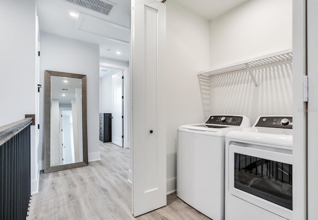 laundry room with washer and clothes dryer and light wood-type flooring