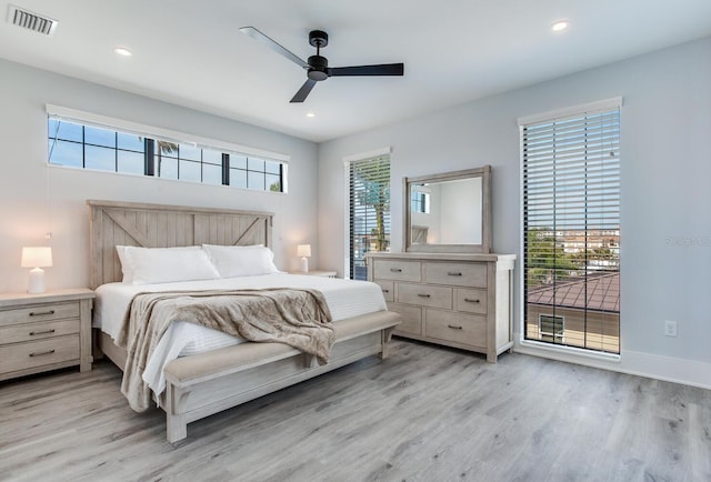 bedroom featuring ceiling fan, light hardwood / wood-style floors, and multiple windows