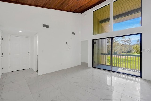 unfurnished room with wooden ceiling and a high ceiling