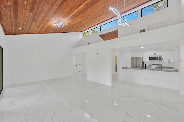 unfurnished living room with high vaulted ceiling, wood ceiling, and sink