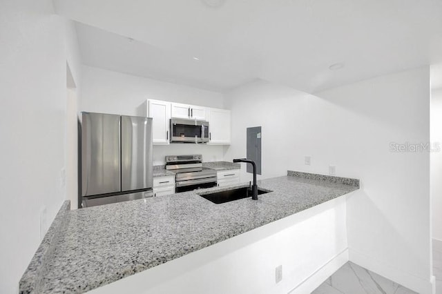 kitchen featuring sink, white cabinets, kitchen peninsula, appliances with stainless steel finishes, and light stone countertops