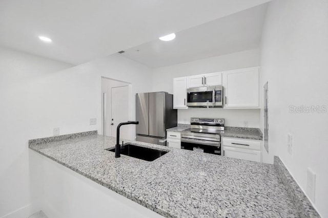 kitchen with light stone counters, sink, kitchen peninsula, white cabinetry, and appliances with stainless steel finishes