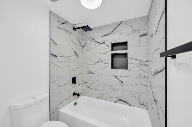 bathroom with tiled shower / bath combo and toilet