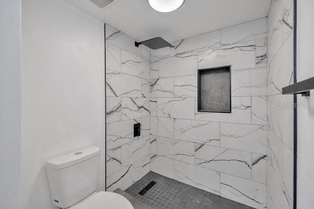 bathroom with tiled shower and toilet