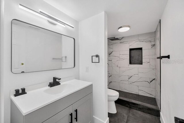 bathroom with vanity, tile patterned flooring, toilet, and tiled shower