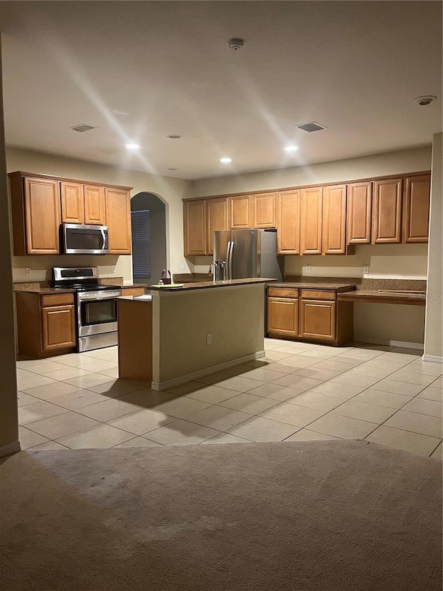 kitchen featuring a center island with sink, light tile patterned floors, sink, and appliances with stainless steel finishes