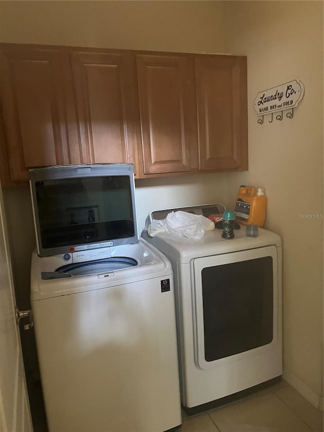 laundry area with cabinets, light tile patterned floors, and washing machine and clothes dryer