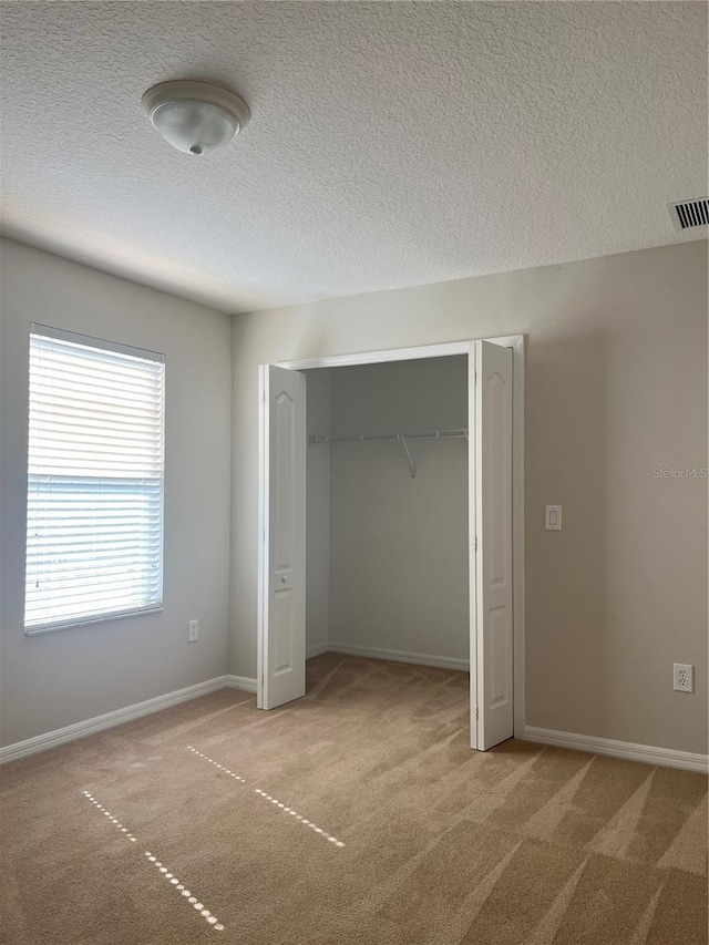 unfurnished bedroom featuring carpet flooring, a closet, and a textured ceiling