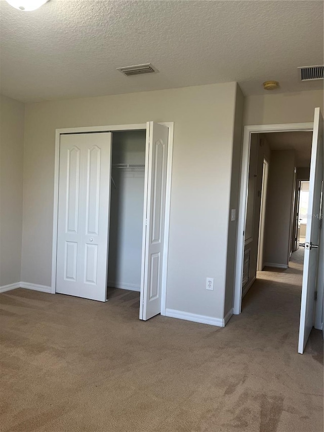 unfurnished bedroom featuring carpet flooring, a textured ceiling, and a closet