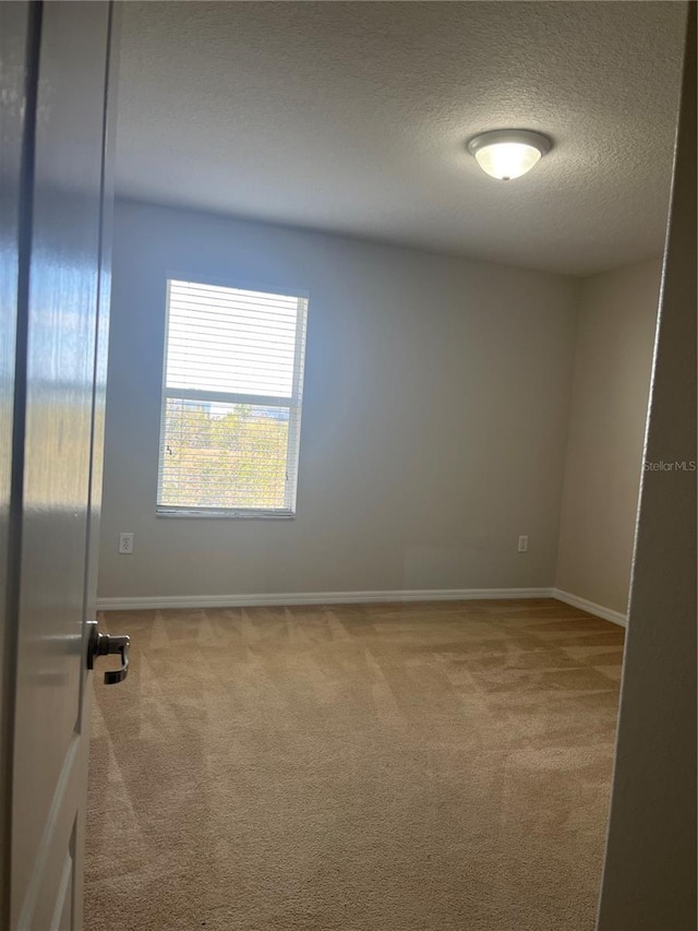 carpeted spare room with a textured ceiling