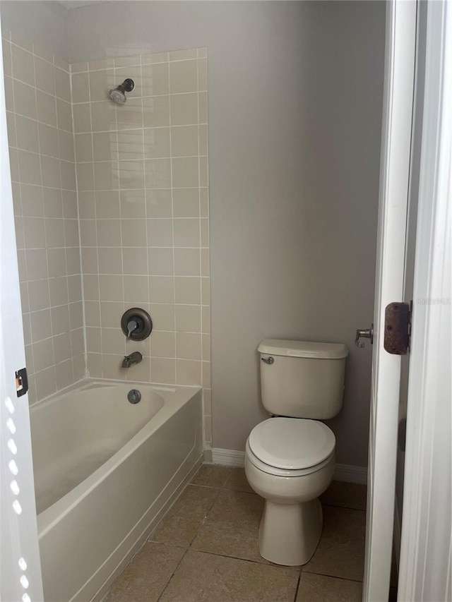 bathroom featuring tile patterned flooring, tiled shower / bath combo, and toilet