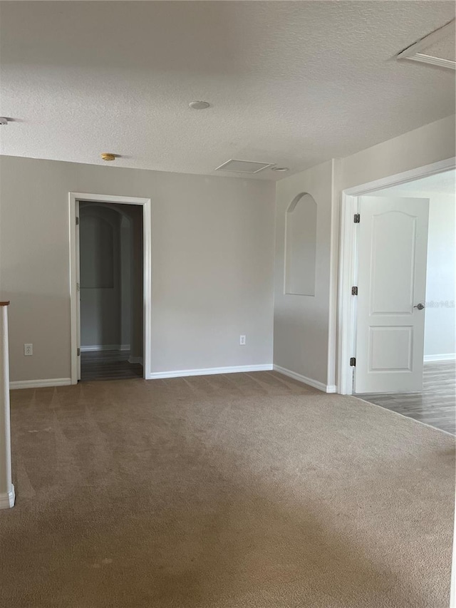 unfurnished room featuring a textured ceiling and dark colored carpet