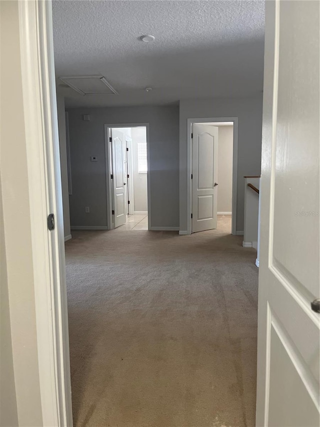 corridor with light colored carpet and a textured ceiling