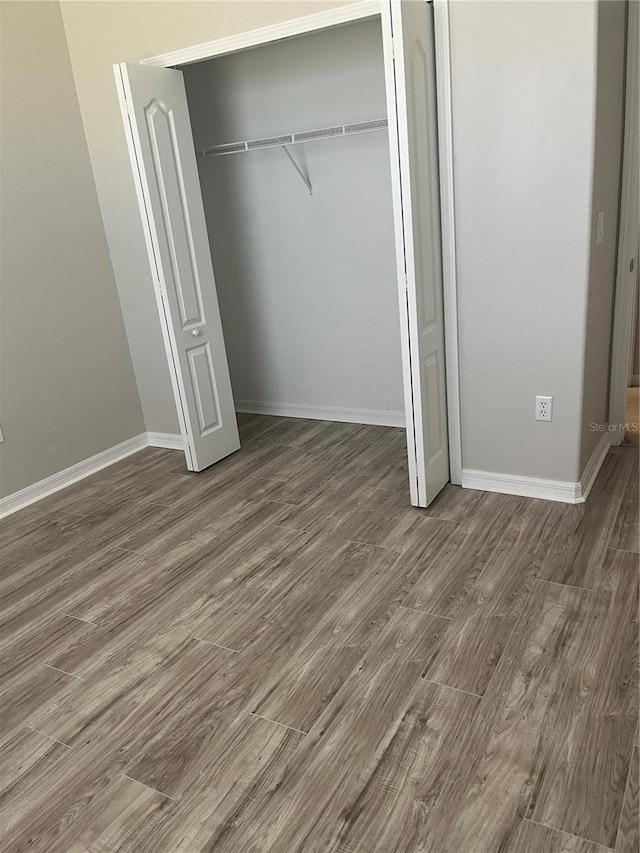 unfurnished bedroom with dark hardwood / wood-style flooring and a closet