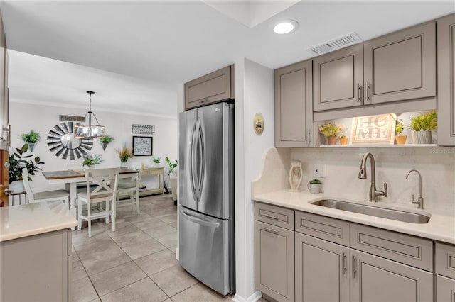 kitchen with sink, stainless steel fridge, ornamental molding, light tile patterned floors, and decorative light fixtures