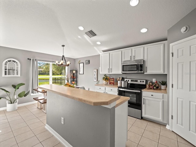 kitchen with white cabinetry, a center island, a notable chandelier, and appliances with stainless steel finishes