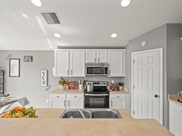 kitchen with white cabinetry, stainless steel appliances, and vaulted ceiling