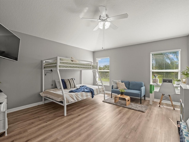 bedroom with ceiling fan, wood-type flooring, and a textured ceiling