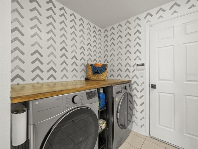 clothes washing area featuring washer and dryer and light tile patterned floors