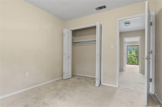 unfurnished bedroom with light colored carpet and a closet