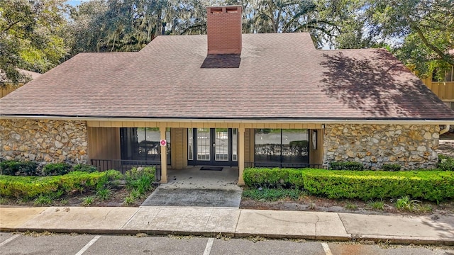 507 NW 39th Rd Unit 318, Gainesville, FL 32607 - mid-century home featuring stone siding, a chimney, french doors, and roof with shingles