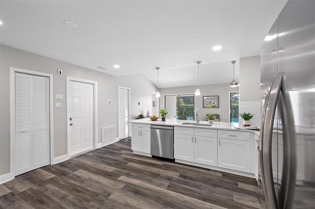 kitchen featuring sink, hanging light fixtures, white cabinetry, stainless steel appliances, and dark wood-type flooring