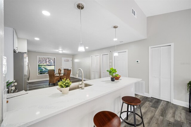 kitchen featuring a breakfast bar area, stainless steel fridge, white cabinets, and pendant lighting