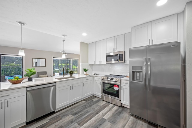 kitchen with sink, appliances with stainless steel finishes, pendant lighting, and white cabinets